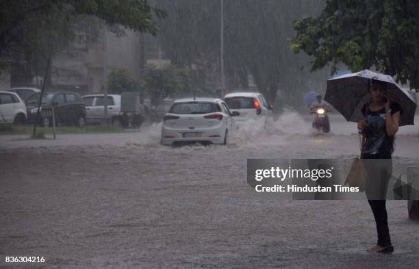 Girl stands holding umbrella waiting for transport during heavy rain at on August 21 2017 in Chandigarh, India. Heavy rainfall on morning brought the...