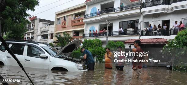 People checking engine of car which broke down due to water-logging at phase 5 after heavy rains on August 21, 2017 in Mohali, India. Heavy rainfall...