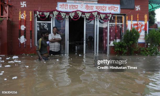 People stand in thigh deep water at Gaushala at Sector 45 after heavy rains on August 21 2017 in Chandigarh, India. Heavy rainfall on morning brought...