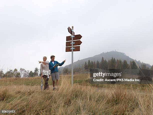 hikers at trail fork, point in opposite directions - backpacker road stock pictures, royalty-free photos & images