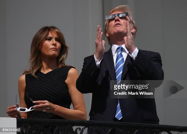 President Donald Trump wears special glasses as he looks up toward the Solar Eclipse while standing with his wife first lady Melania Trump on the...