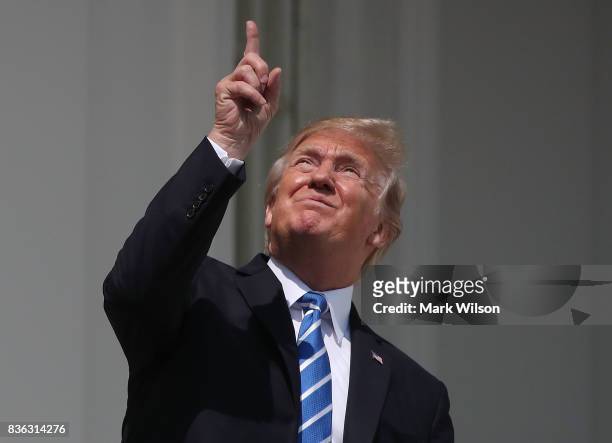 President Donald Trump looks up toward the Solar Eclipse on the Truman Balcony at the White House on August 21, 2017 in Washington, DC. Millions of...