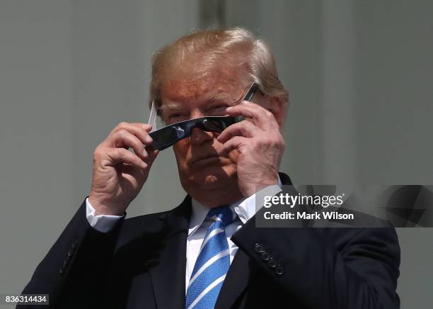 President Donald Trump puts on special glasses to look at the Solar Eclipse on the Truman Balcony at the White House on August 21, 2017 in...