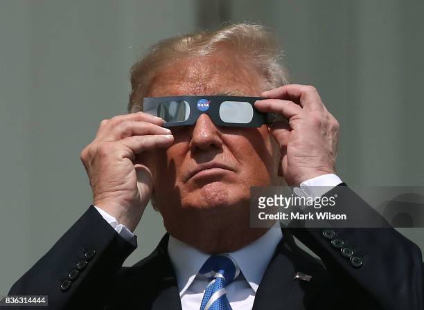 President Donald Trump puts on special glasses to look at the Solar Eclipse on the Truman Balcony at the White House on August 21, 2017 in...