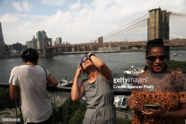 People watch a partial solar eclipse from the roof deck at the 1 Hotel Brooklyn Bridge on August 21, 2017 in the Brooklyn borough of New York City....