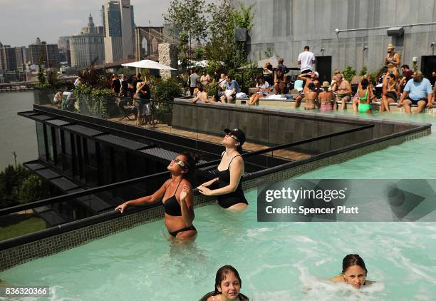 People watch a partial solar eclipse from the roof deck at the 1 Hotel Brooklyn Bridge on August 21, 2017 in the Brooklyn borough of New York City....