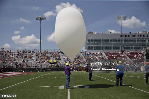 Man holds a weather balloon carrying scientific equipment before launch during a solar eclipse viewing event on the campus of Southern Illinois...