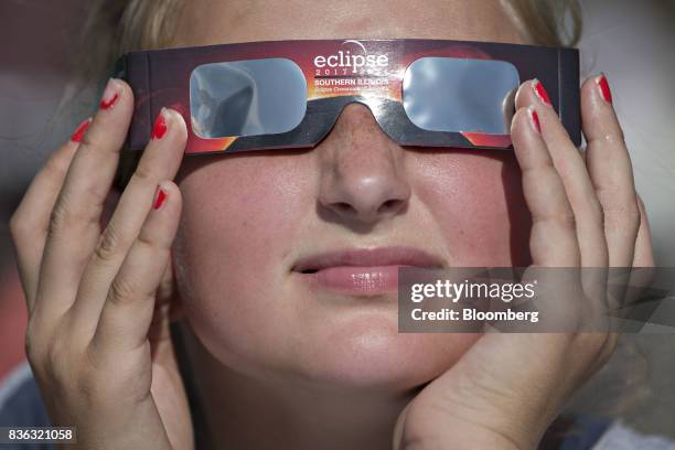 Girl wears solar viewing glasses while looking at the sun during a solar eclipse viewing event on the campus of Southern Illinois University in...