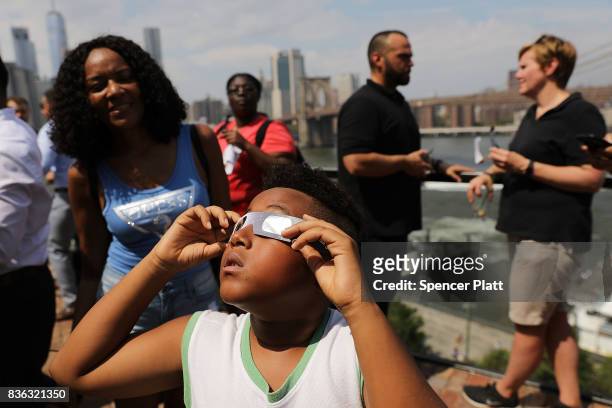 Child watches a partial solar eclipse from the roof deck at the 1 Hotel Brooklyn Bridge on August 21, 2017 in the Brooklyn borough of New York City....