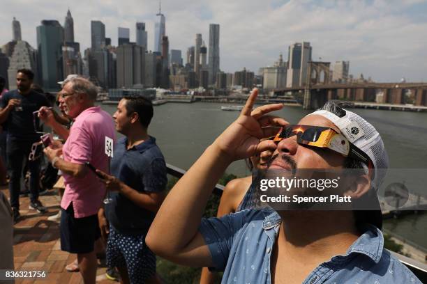 People watch a partial solar eclipse from the roof deck at the 1 Hotel Brooklyn Bridge on August 21, 2017 in the Brooklyn borough of New York City....