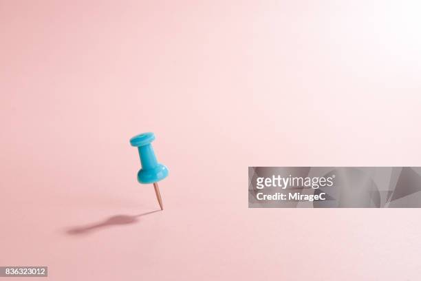 turquoise thumbtack against pink colored background - insight guidance stock-fotos und bilder