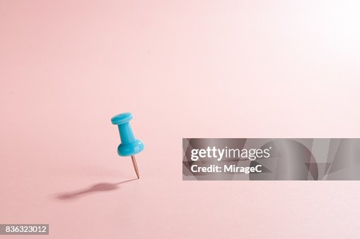 Turquoise Thumbtack Against Pink Colored Background Turquoise Thumbtack Against Pink Colored Background
