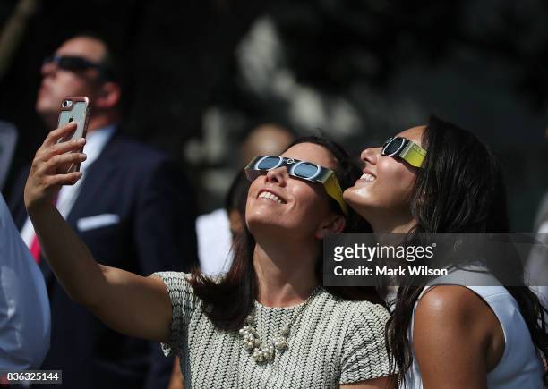 Two White House staff members take a selfie while wearing special glasses to view the solar eclipse, on the South Lawn at the White House on August...