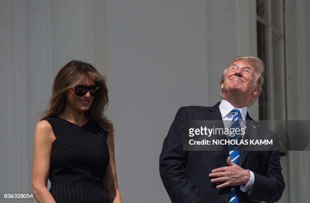 President Donald Trump and First Lady Melania Trump look up at the partial solar eclipse from the balcony of the White House in Washington, DC, on...