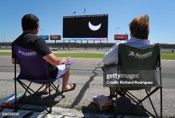 Spectators watch the solar eclipse as it is broadcast on Big Hoss at Texas Motor Speedway on August 21, 2017 in Fort Worth, Texas. Millions of people...