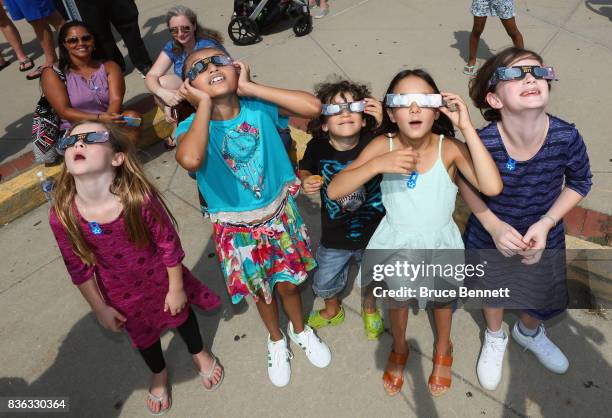 Spectators look skyward during a partial eclipse of the sun on August 21, 2017 at the Cradle of Aviation Museum in Garden City, New York. Millions of...