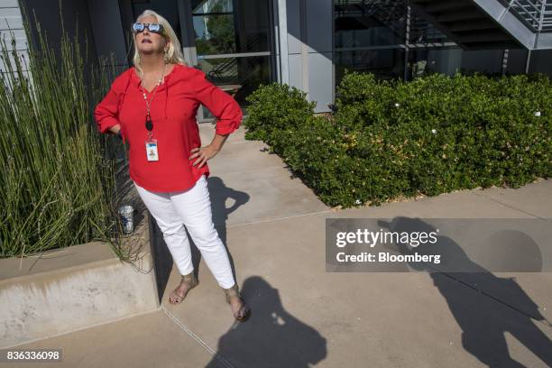 Woman wears solar viewing glasses while looking at the sun during a solar eclipse at the California Independent System Operator headquarters in...