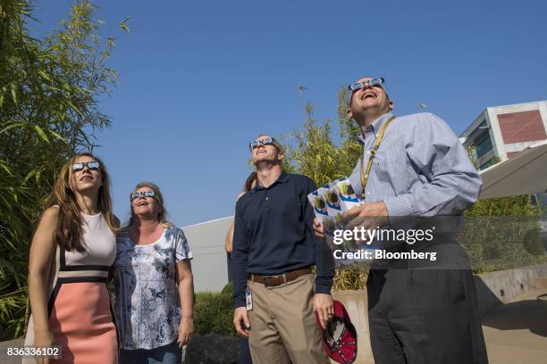 People wear solar viewing glasses while looking at the sun during a solar eclipse at the California Independent System Operator headquarters in...