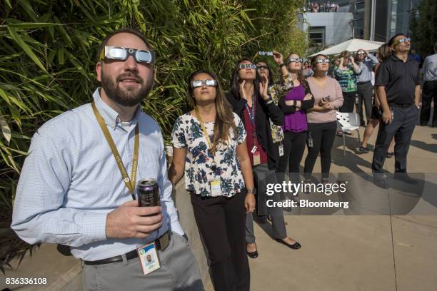 People wear solar viewing glasses while looking at the sun during a solar eclipse at the California Independent System Operator headquarters in...