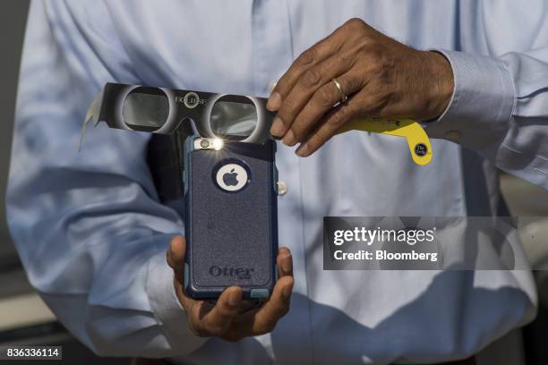 Man holds solar viewing glasses over the camera of an Apple Inc. IPhone to take a photograph of the solar eclipse at the California Independent...