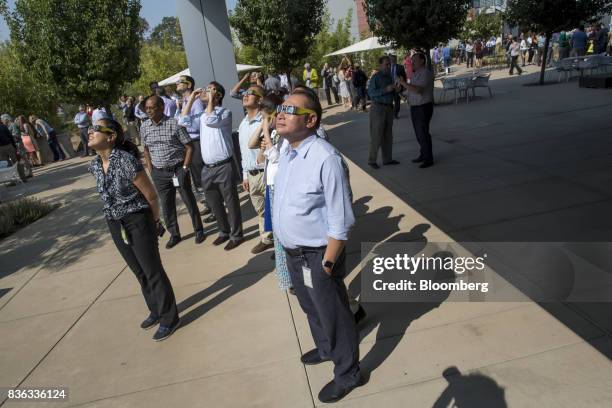 People wear solar viewing glasses while looking at the sun during a solar eclipse at the California Independent System Operator headquarters in...