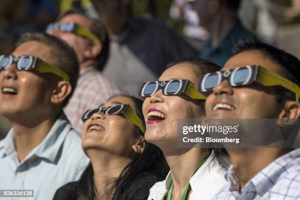 People wear solar viewing glasses while looking at the sun during a solar eclipse at the California Independent System Operator headquarters in...