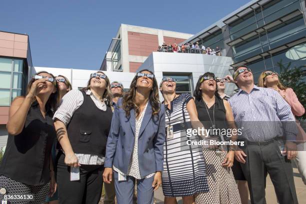 People wear solar viewing glasses while looking at the sun during a solar eclipse at the California Independent System Operator headquarters in...