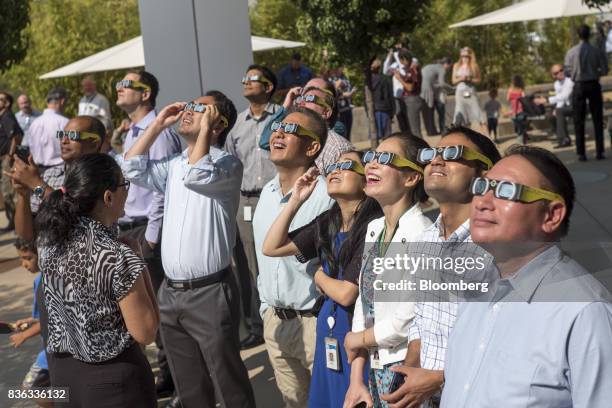 People wear solar viewing glasses while looking at the sun during a solar eclipse at the California Independent System Operator headquarters in...