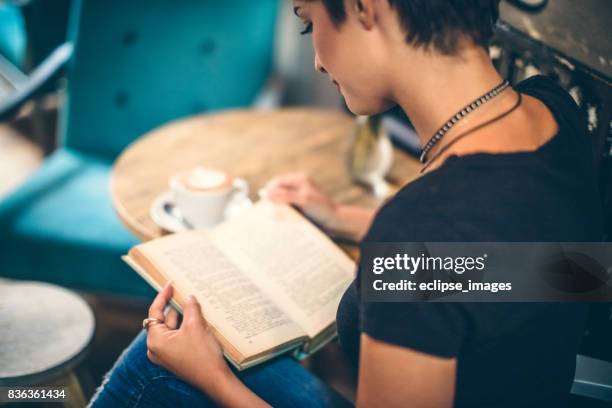 mädchen trinken kaffee und lesen buch im café - stranger stock-fotos und bilder