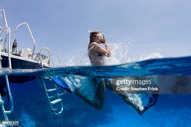 snorkeler enters water from boat - sporttauchen stock-fotos und bilder