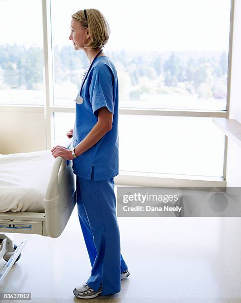nurse standing at end of patient's bed in hospital - uniform imagens e fotografias de stock
