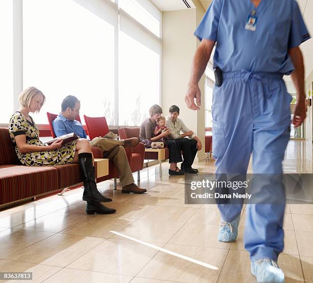 people in waiting area of hospital with surgeon wa - waiting room fotografías e imágenes de stock