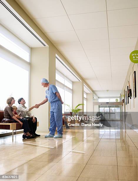 male surgeon greeting patient's family in hospital - couple shaking hands with doctor stock-fotos und bilder