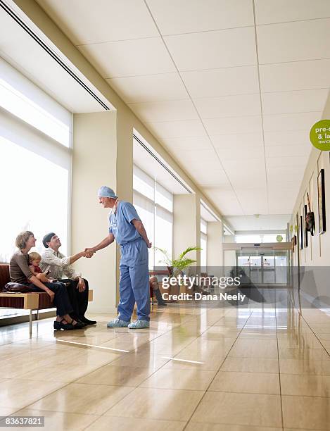 male surgeon greeting patient's family in hospital - couple shaking hands with doctor stock pictures, royalty-free photos & images