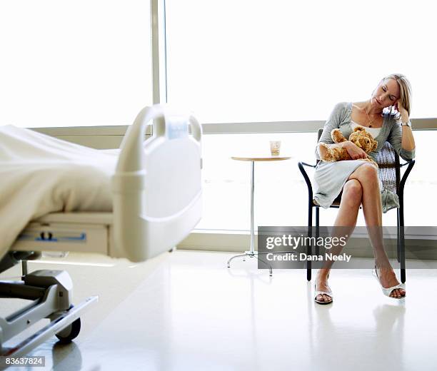 mother resting near child's hospital bed - unhappy woman blonde glasses stock pictures, royalty-free photos & images