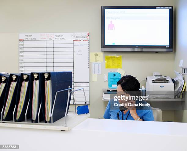 female nurse on phone in outpatient/recovery       - schwesterntisch stock-fotos und bilder