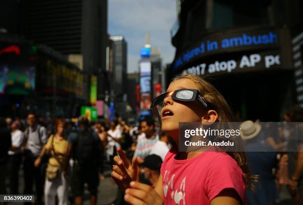 Girl observes the total solar eclipse with solar eclipse glasses at the Times Square in New York City, United States on August 21, 2017.