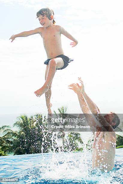 father playfully tossing son in air in pool - dad throwing kid in air stockfoto's en -beelden