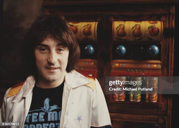 English singer-songwriter and former Wings and Moody Blues guitarist, Denny Laine poses in front of two slot machines in 1981.