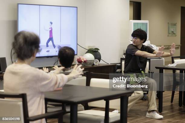 Nursing care worker, right, leads residents to exercise at the As Partners Co. Asheim Nerima Garden nursing home in Tokyo, Japan, on Friday, Aug. 18,...