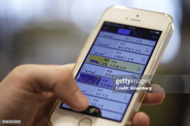 Nursing care worker looks at the residents' sleeping conditions on the "EGAO link" system on an Apple Inc. IPhone in an arranged photograph at the As...