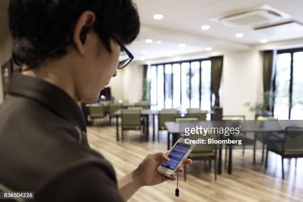 Nursing care worker looks at the residents' sleeping conditions on the "EGAO link" system on an Apple Inc. IPhone in an arranged photograph at the As...