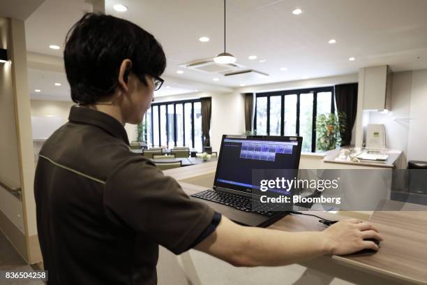 Nursing care worker looks at the residents' sleeping conditions on the "EGAO link" system in an arranged photograph at the As Partners Co.'s Asheim...