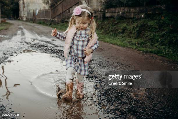 young girl walking in muddy puddle - muddy shoe print stock pictures, royalty-free photos & images