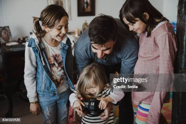 father showing girls images on back of the camera - digital single lens reflex camera stock pictures, royalty-free photos & images