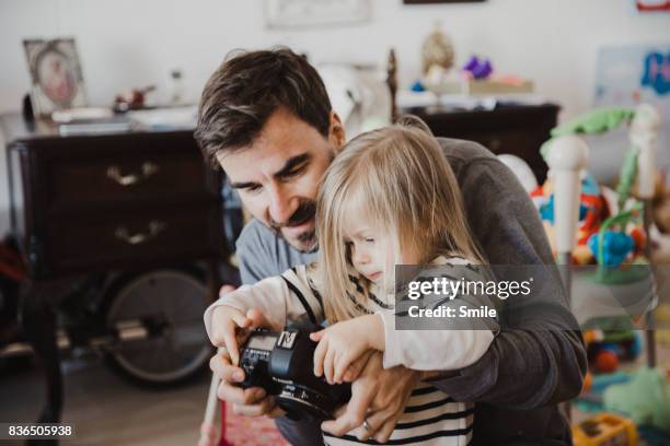 father with daughter viewing images on back of camera - digital single lens reflex camera stock pictures, royalty-free photos & images