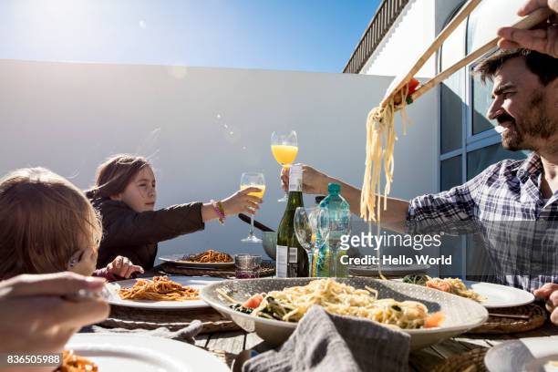 father toasting daughter with orange juice at lunch - family orange juice foto e immagini stock