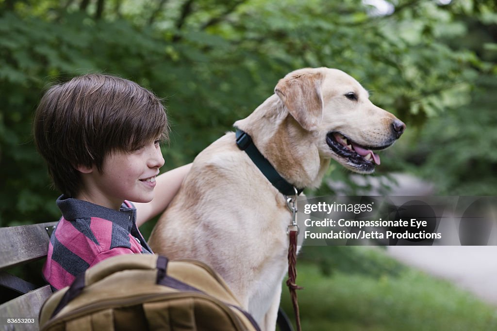 Boy and dog sitting on bench