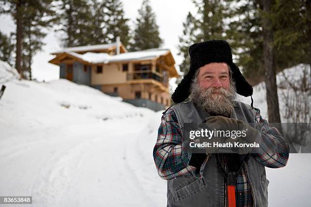 bearded man with snow shovel in front of house in winter, whitefish, montana. - skyffel bildbanksfoton och bilder