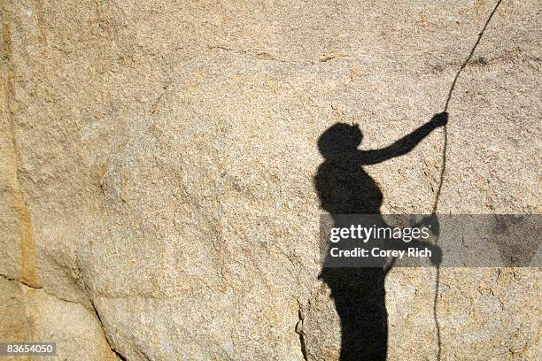 shadow on rock of woman belaying - zekeren stockfoto's en -beelden